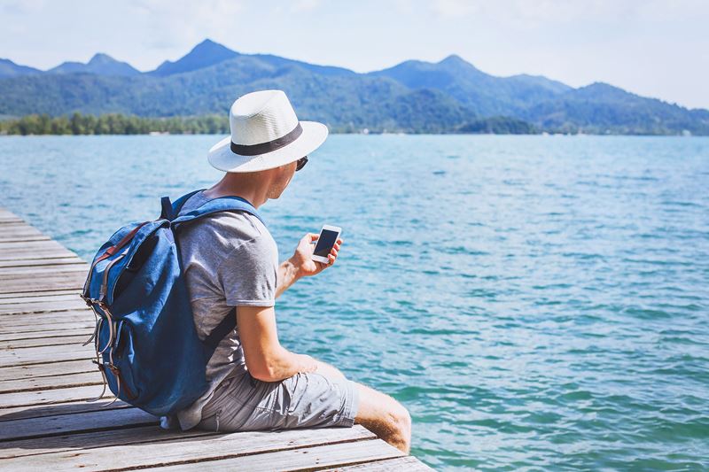 man sitting on dock with cell phone